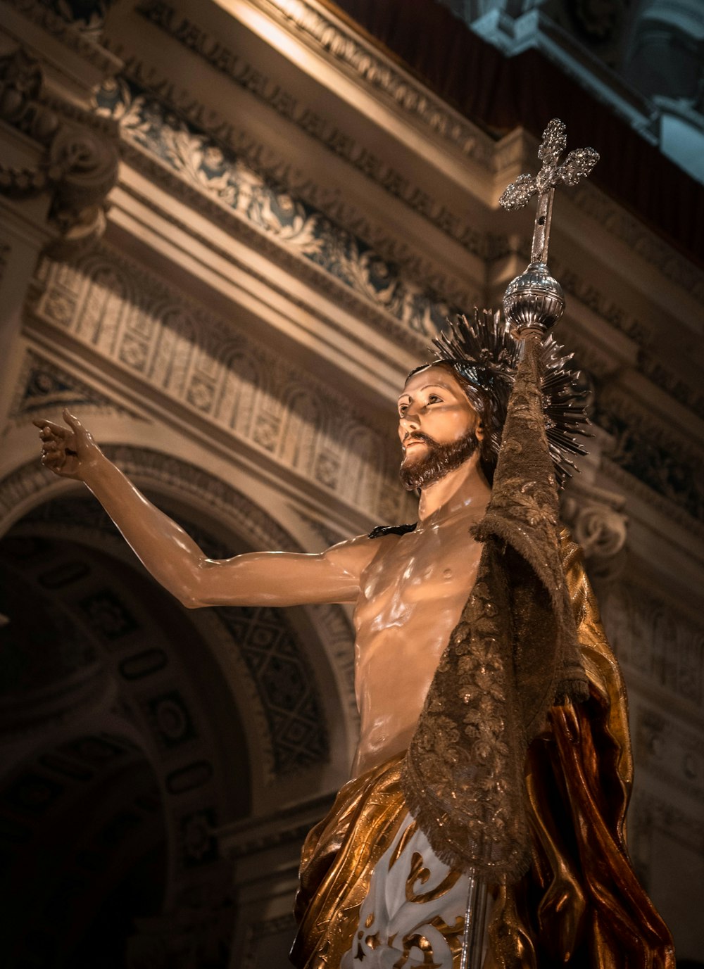 a statue of jesus holding a cross in his hand