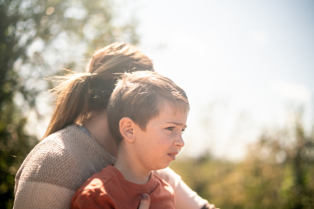 a young girl sitting on the back of a young boy