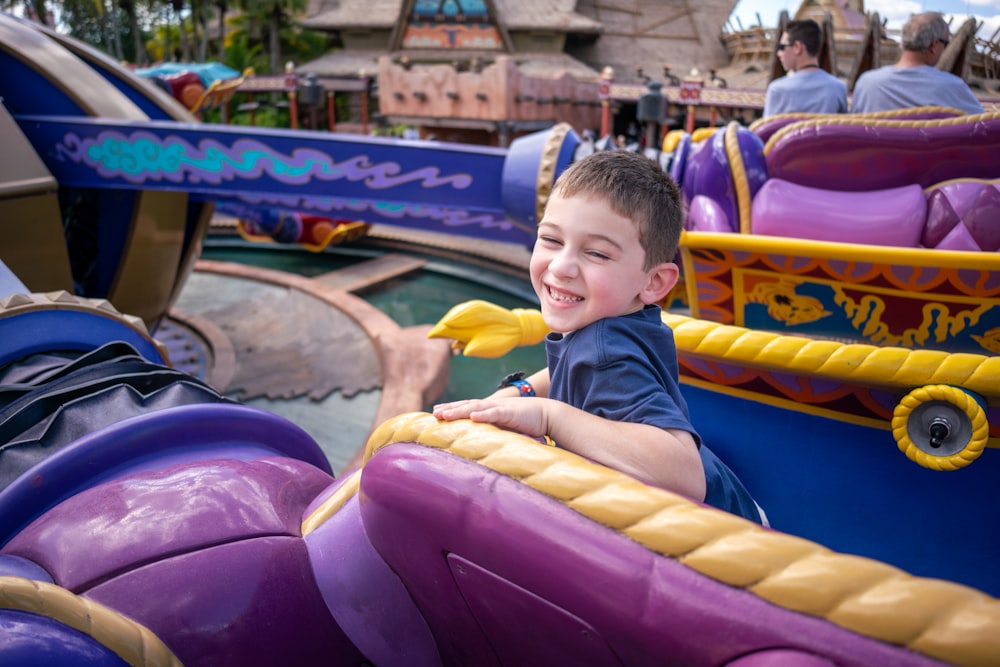 a young boy riding a ride at a theme park