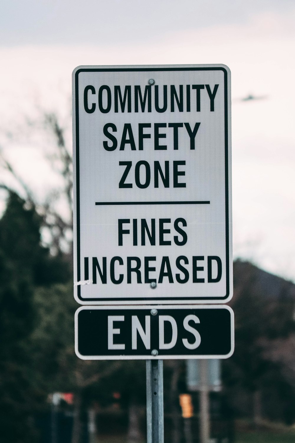 a street sign that says community safety zone fines increase ends
