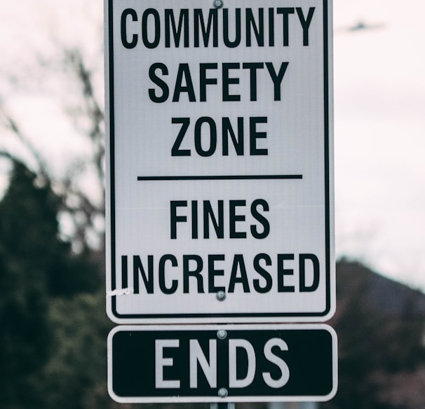 a street sign that says community safety zone fines increase ends