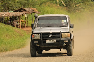 a black truck driving down a dirt road
