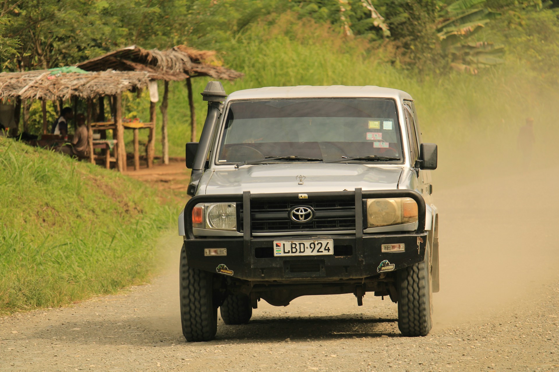 a black truck driving down a dirt road