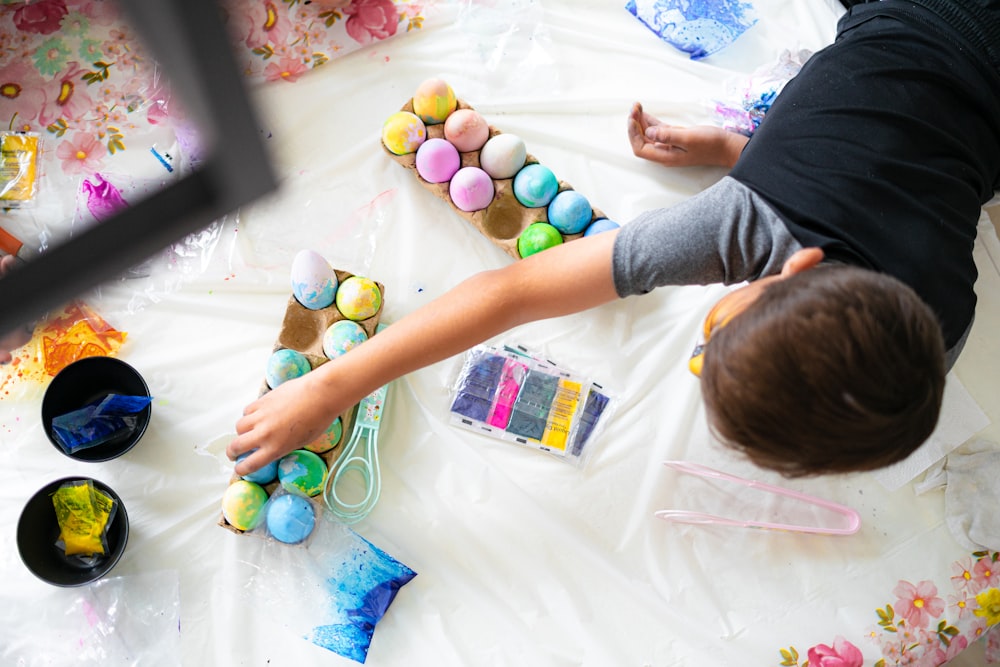 a young boy painting easter eggs on a table