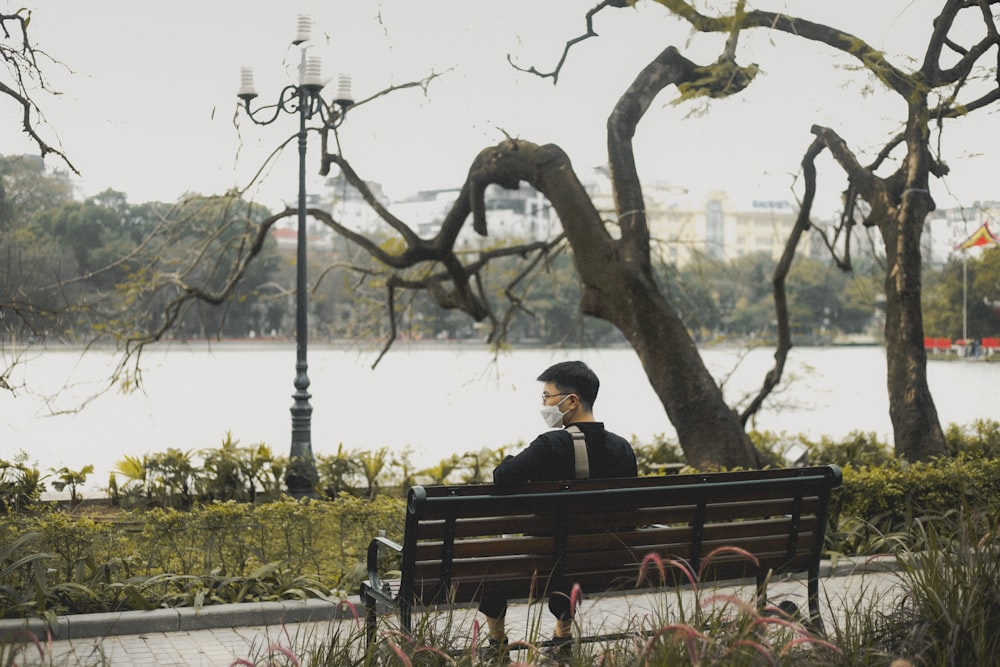 a man sitting on a bench in a park