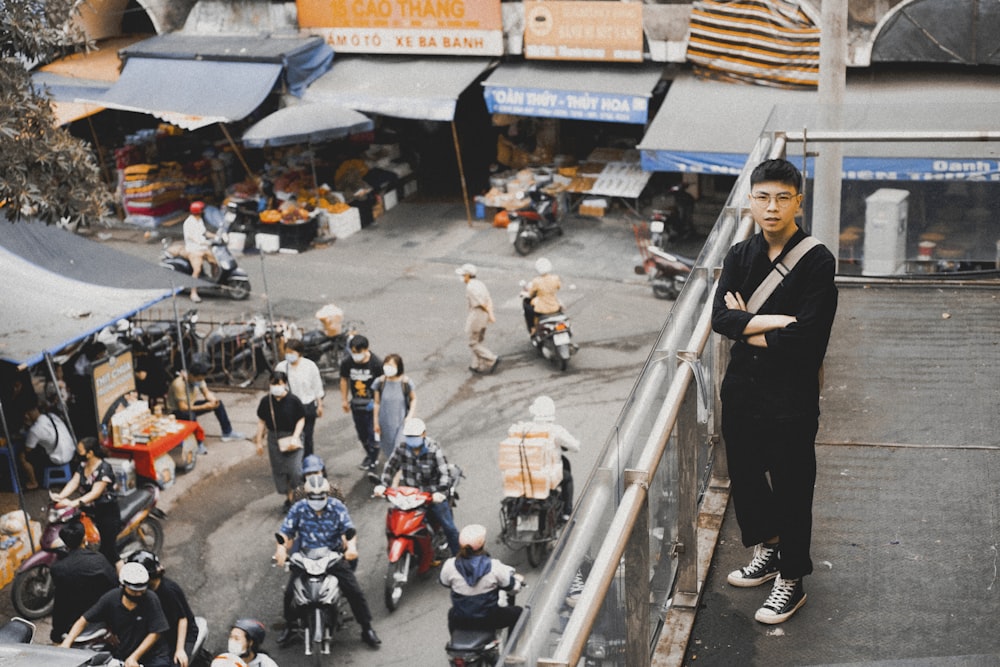 a man standing on a balcony next to a group of people