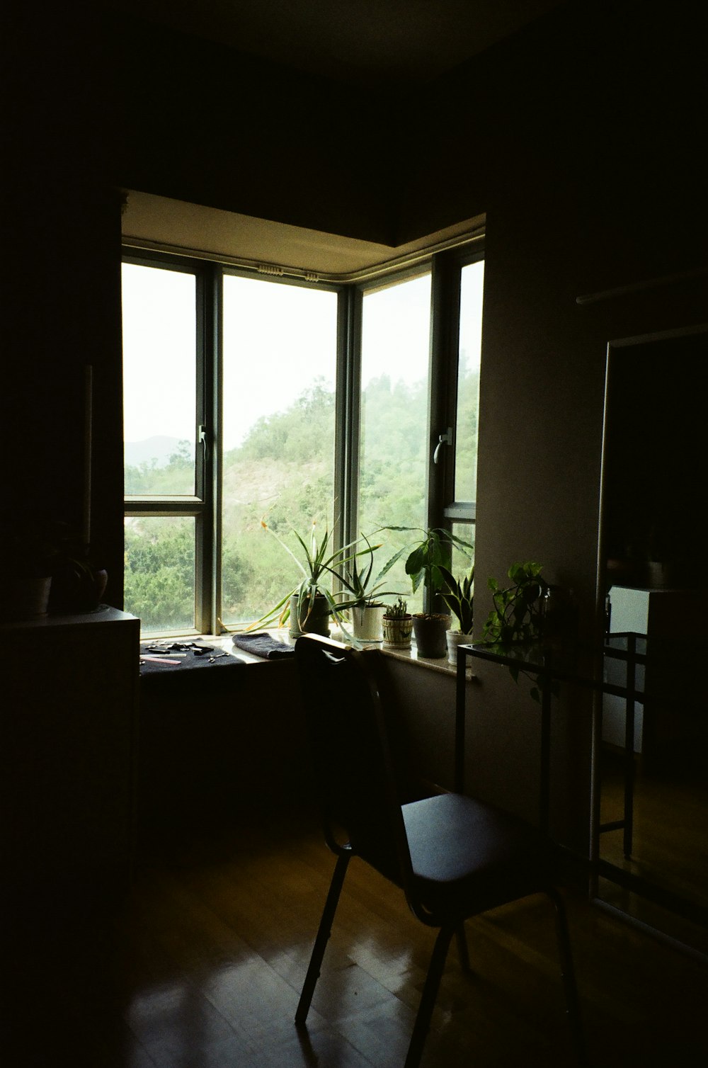 a dark room with a chair and a window