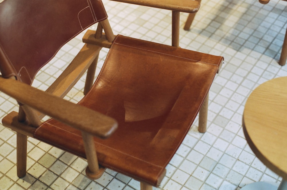a brown leather chair sitting on top of a tiled floor