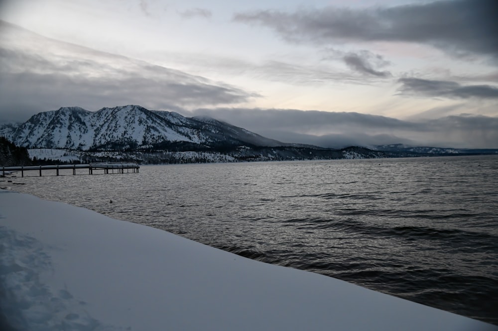 a body of water surrounded by snow covered mountains