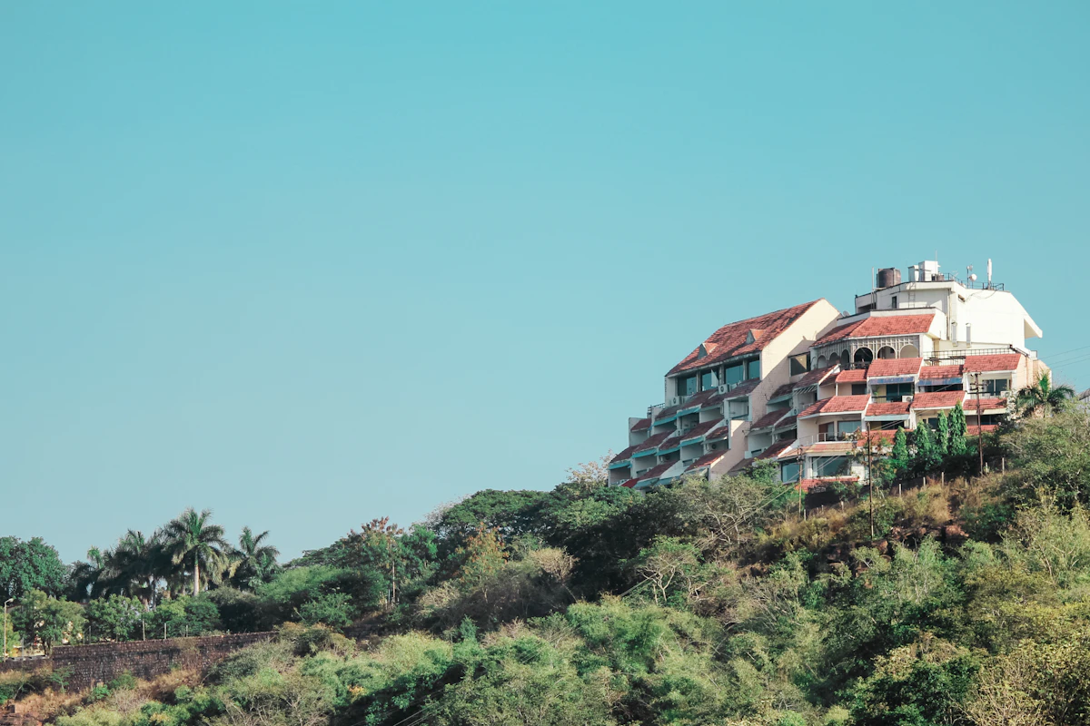 A residential building set on a hillside with trees