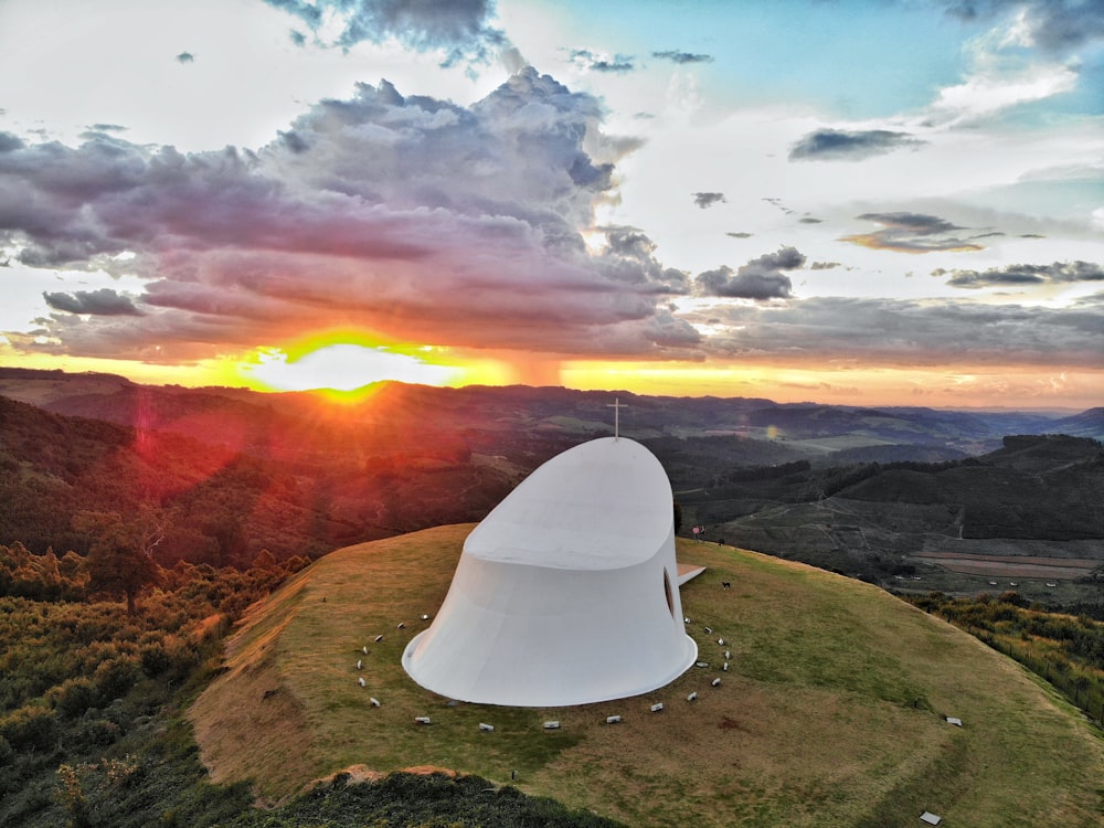 a large white structure sitting on top of a lush green hillside