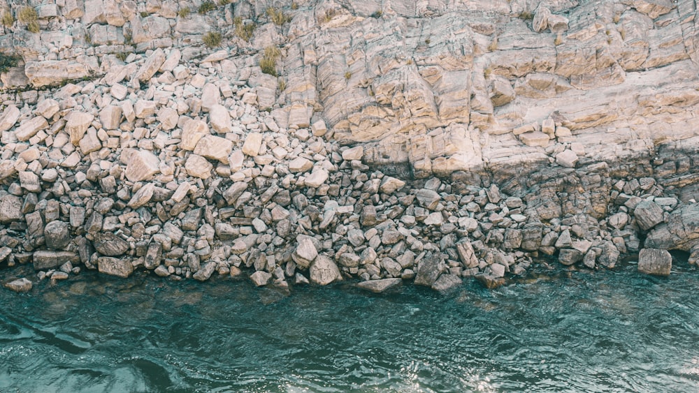 a rock wall next to a body of water