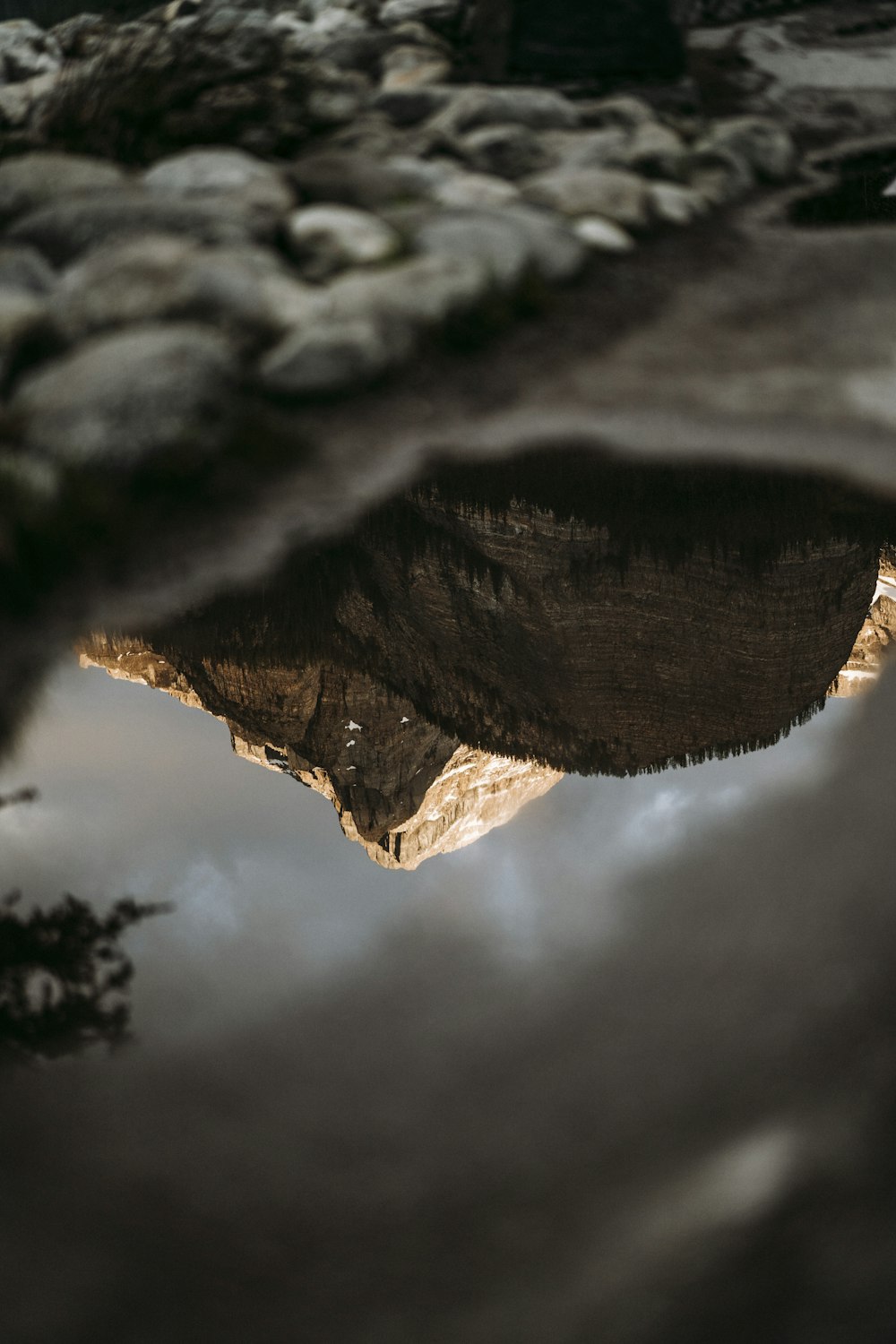 a reflection of a mountain in a puddle of water