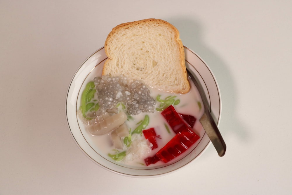 a bowl of food with a spoon and a piece of bread