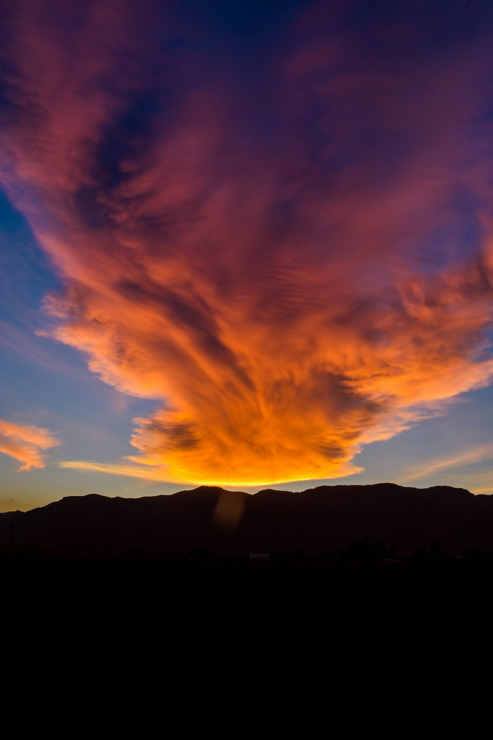 a sunset with clouds and mountains in the background