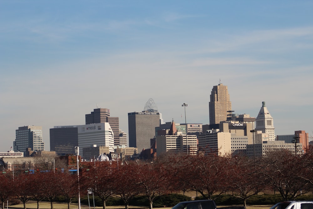 a city skyline with tall buildings and trees in the foreground