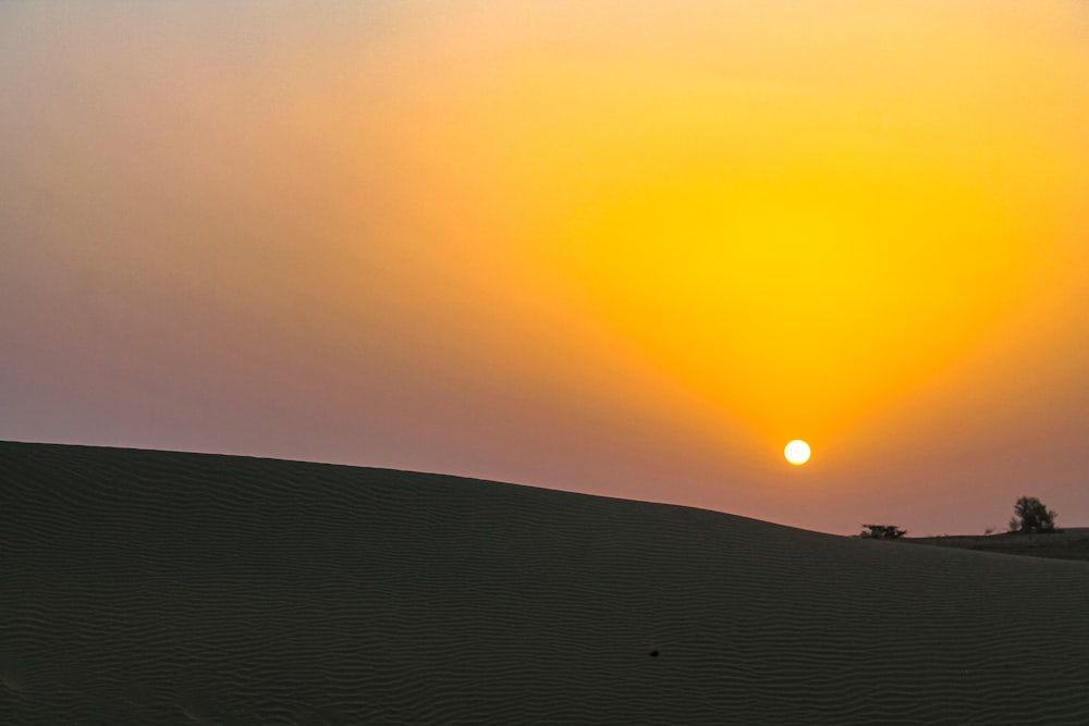 the sun is setting over the sand dunes