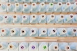 A neatly organized collection of light blue bottles with numbered labels on their tops, arranged in rows. Each bottle has a unique number, with some labels featuring a small colored circle.