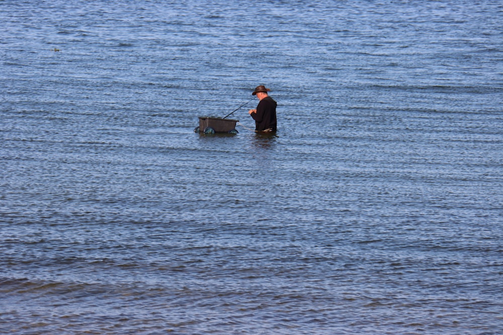 um homem em pé em um corpo de água ao lado de um cão