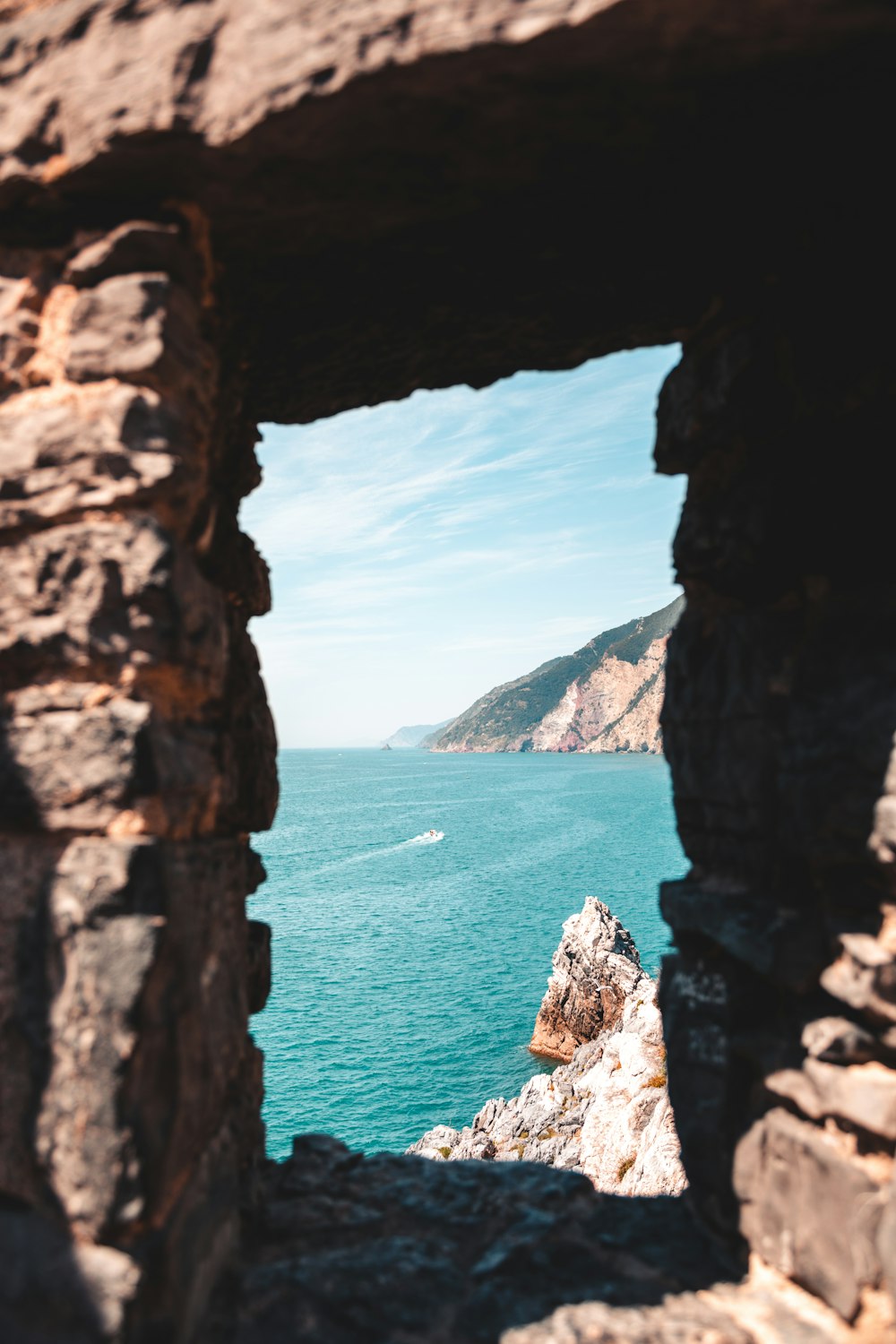 a view of a body of water through a hole in a rock wall