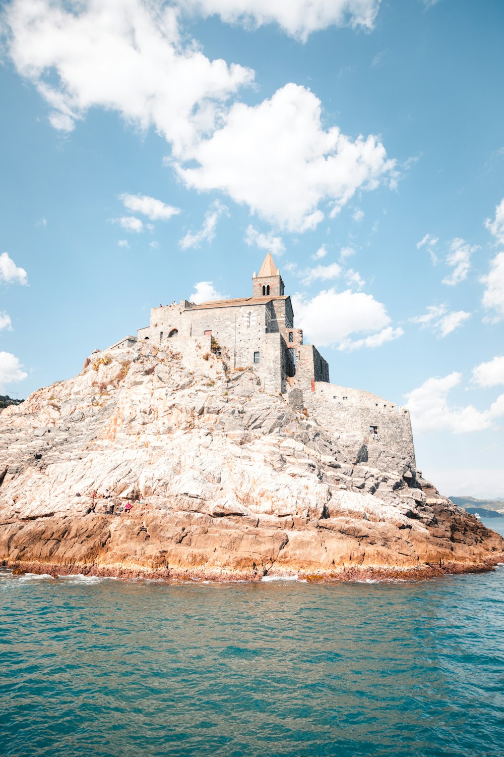 um castelo sentado em cima de uma rocha no meio do oceano