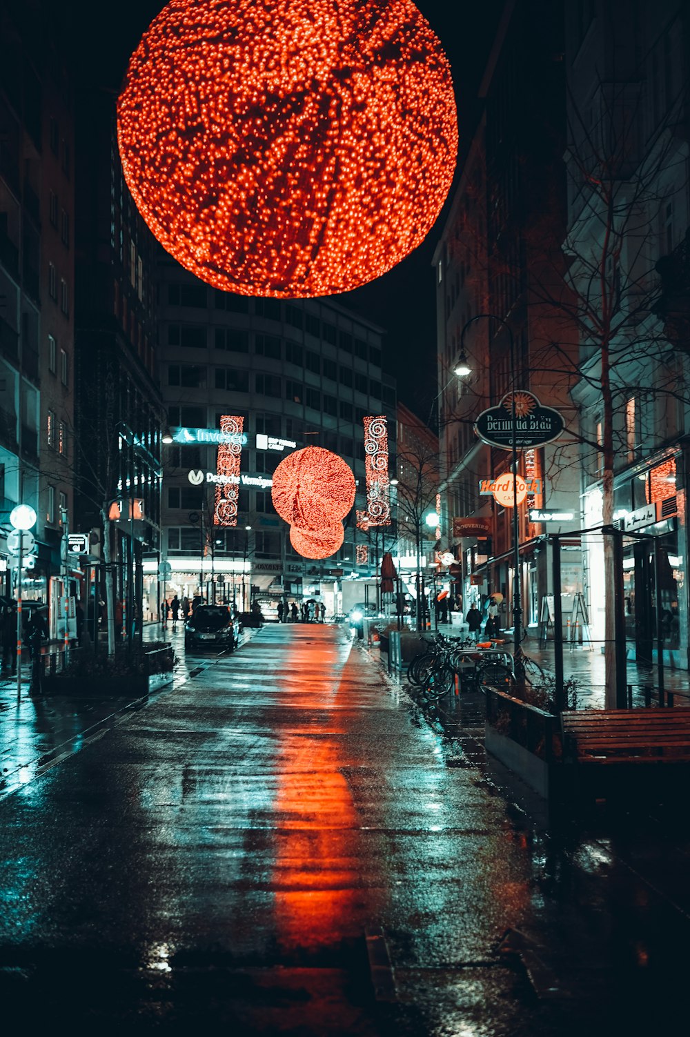 a city street at night with a large red ball hanging from the ceiling