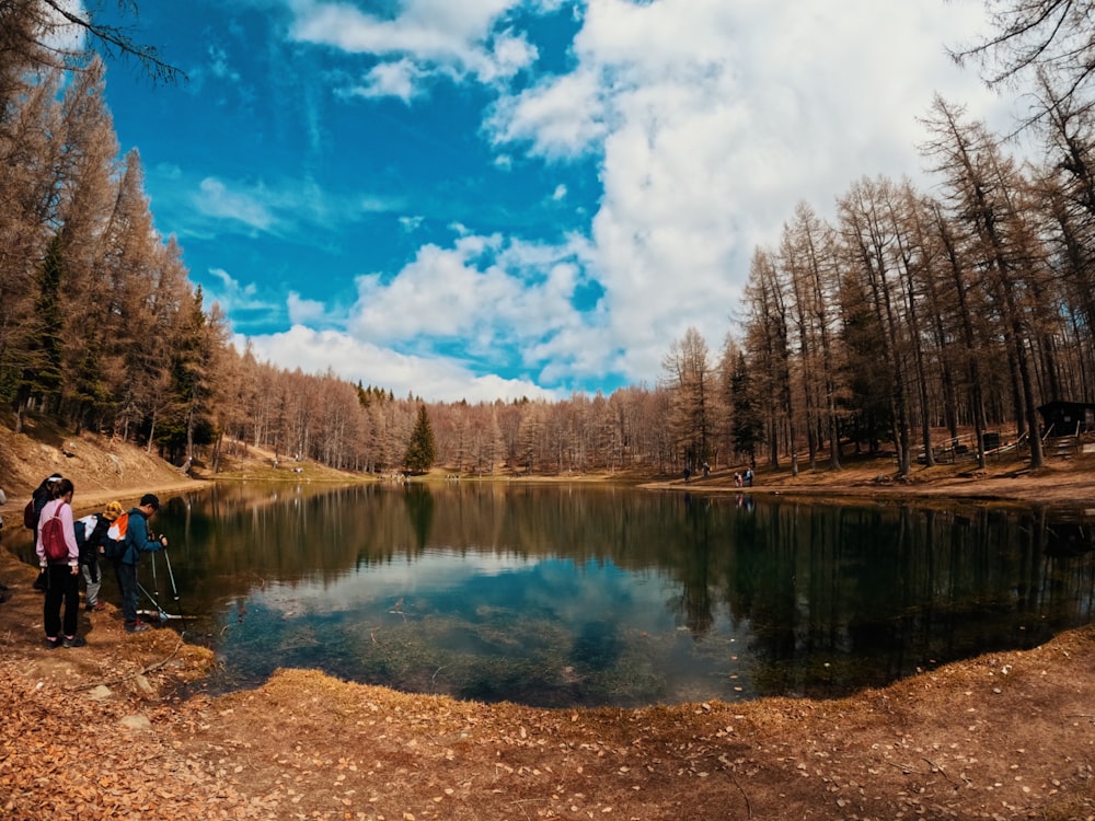 a group of people standing next to a lake