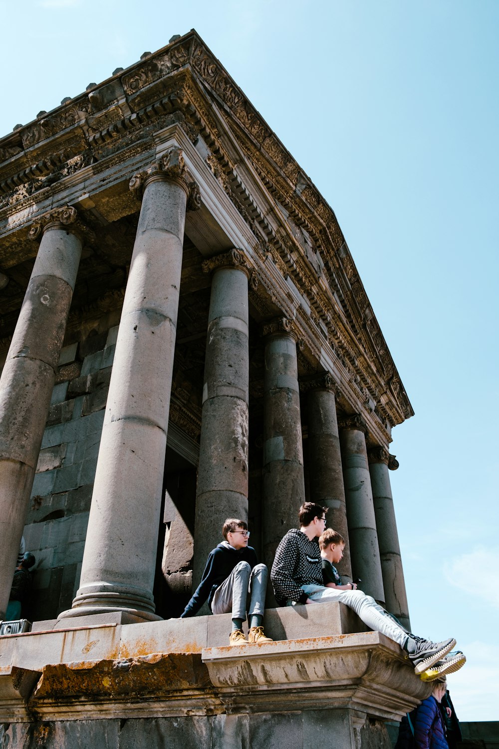 um grupo de pessoas sentadas no topo de um edifício de pedra