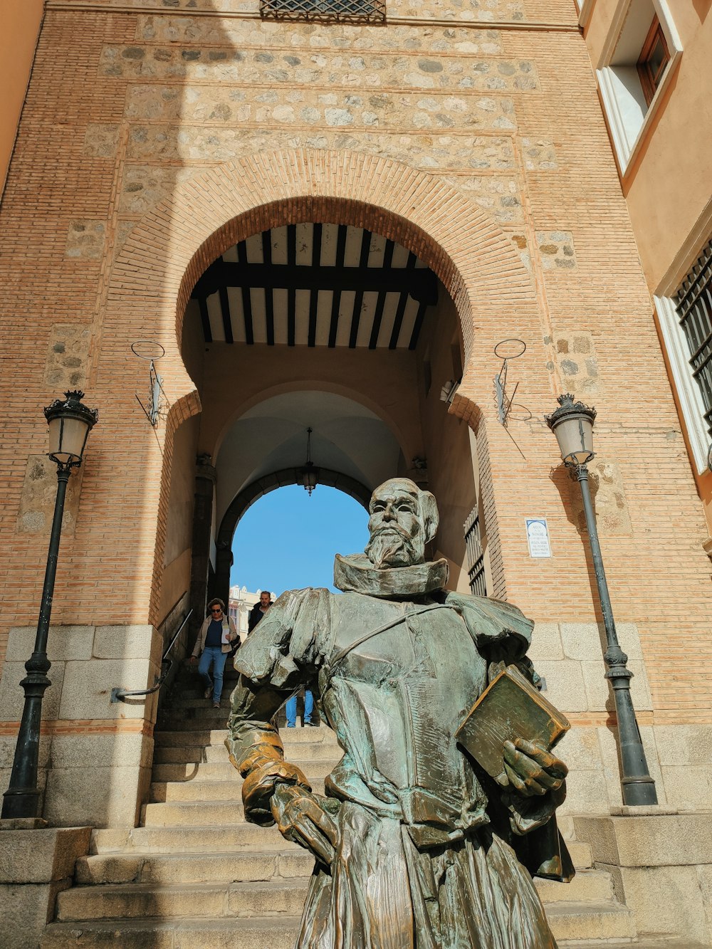 a statue of a man holding a book in front of a building