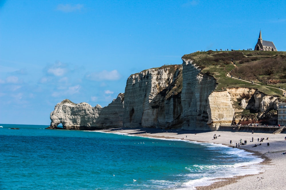 a beach with people walking on the sand and cliffs in the background