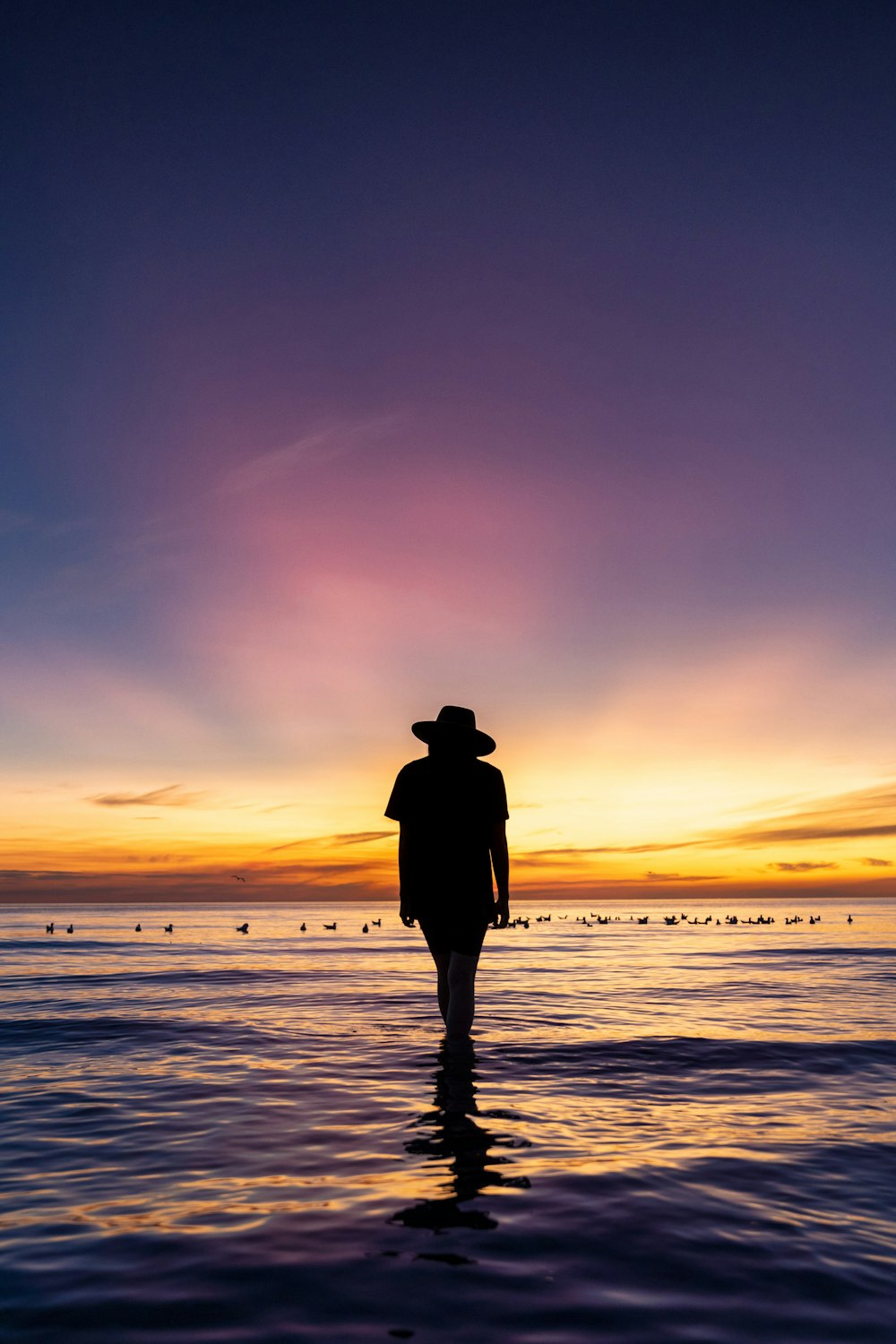 Un hombre parado en el agua al atardecer