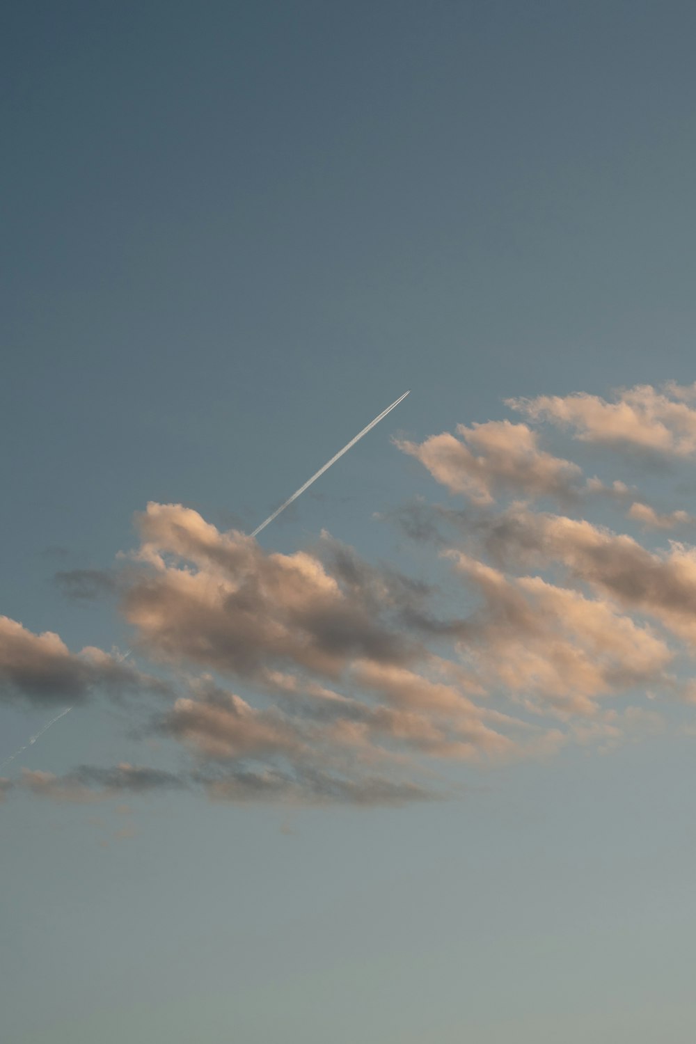 a plane flying in the sky with a contrail in the background