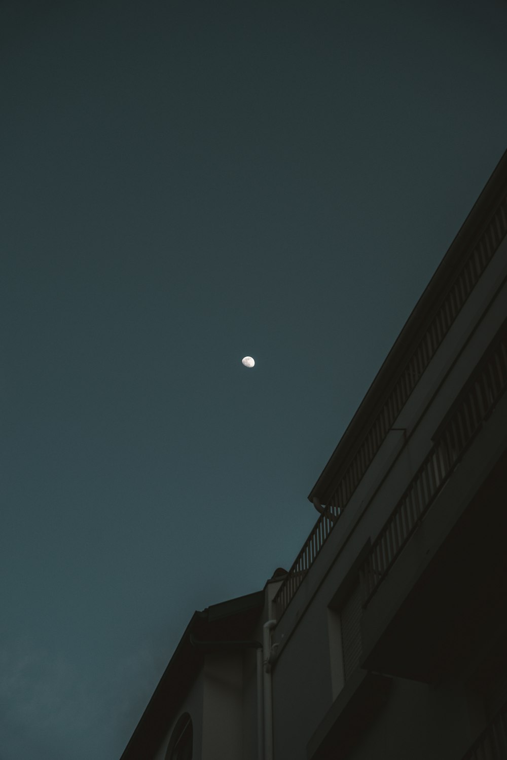 a full moon is seen in the sky above a building