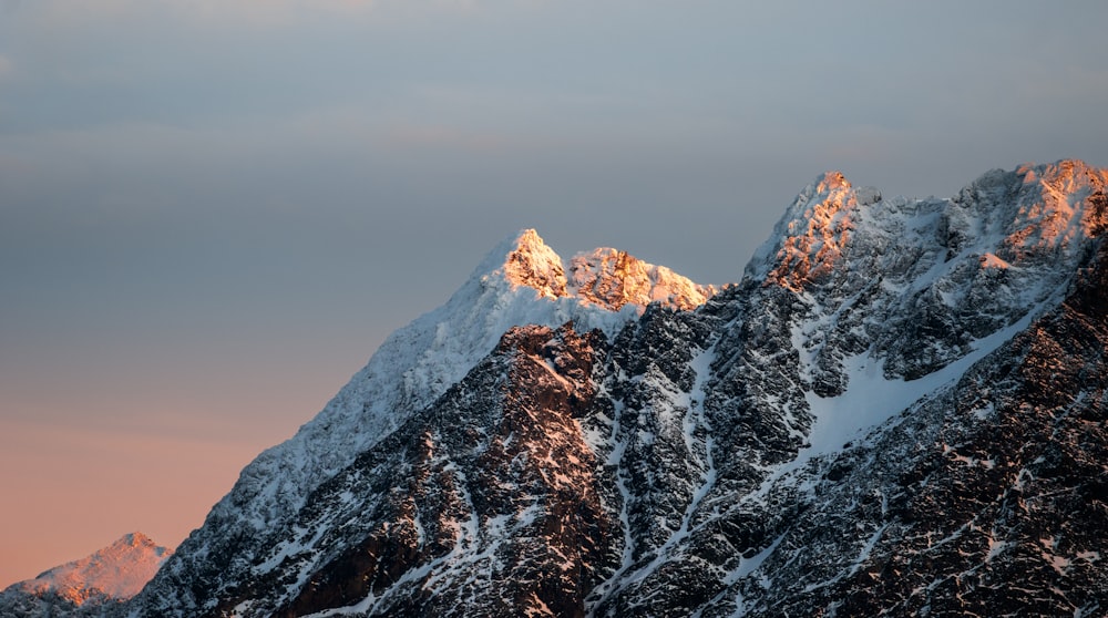 a mountain covered in snow under a cloudy sky