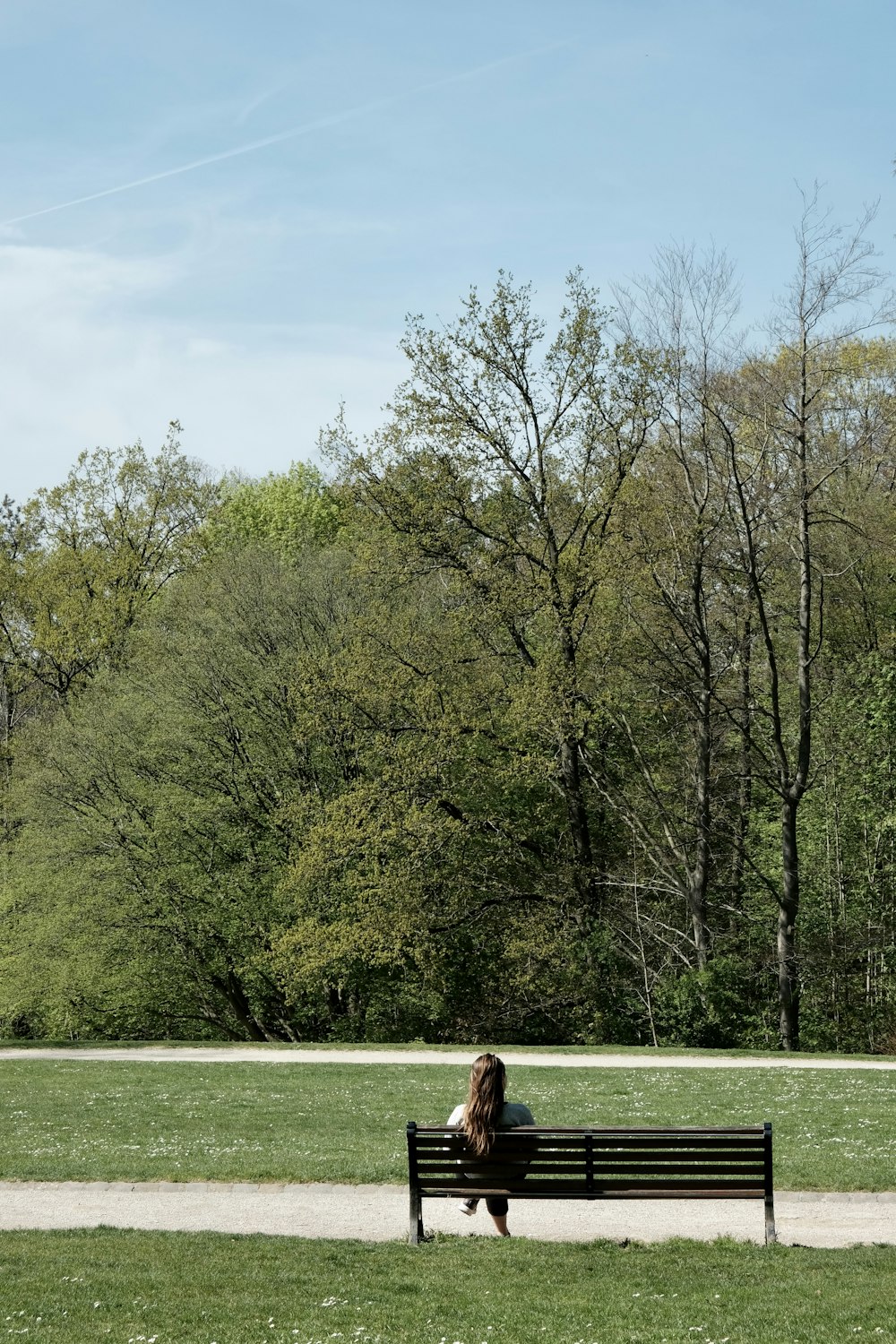 a woman sitting on a bench in a park