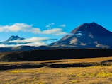 a large mountain with a few clouds in the sky