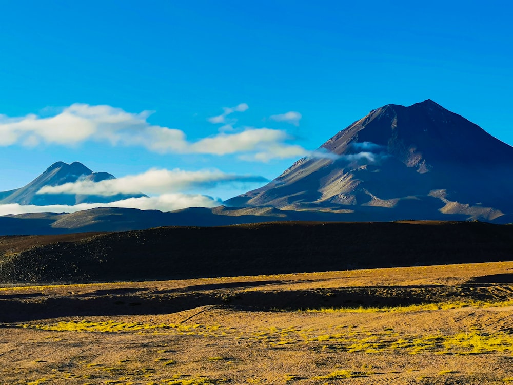 a large mountain with a few clouds in the sky