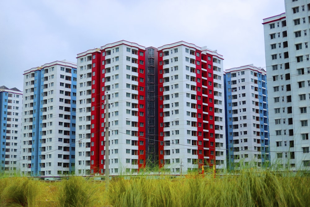 Una hilera de edificios de apartamentos multicolores con hierba alta frente a ellos