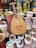 A wooden string instrument is positioned among an assortment of vibrant, painted clay pots and vases. The pots feature various colors and intricate patterns, including floral and geometric designs. The textures and colors create a lively and culturally rich display.