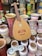 A wooden string instrument is positioned among an assortment of vibrant, painted clay pots and vases. The pots feature various colors and intricate patterns, including floral and geometric designs. The textures and colors create a lively and culturally rich display.
