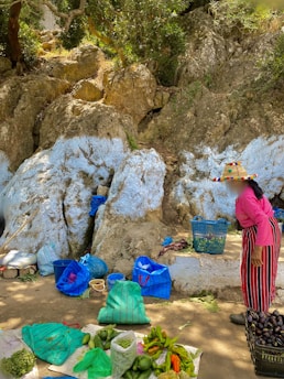 a woman standing next to a pile of fruit and vegetables