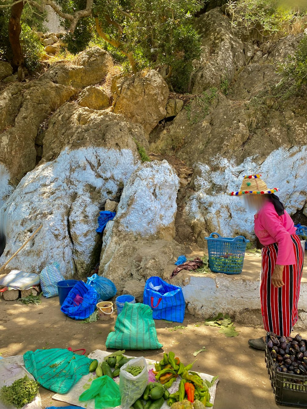 a woman standing next to a pile of fruit and vegetables