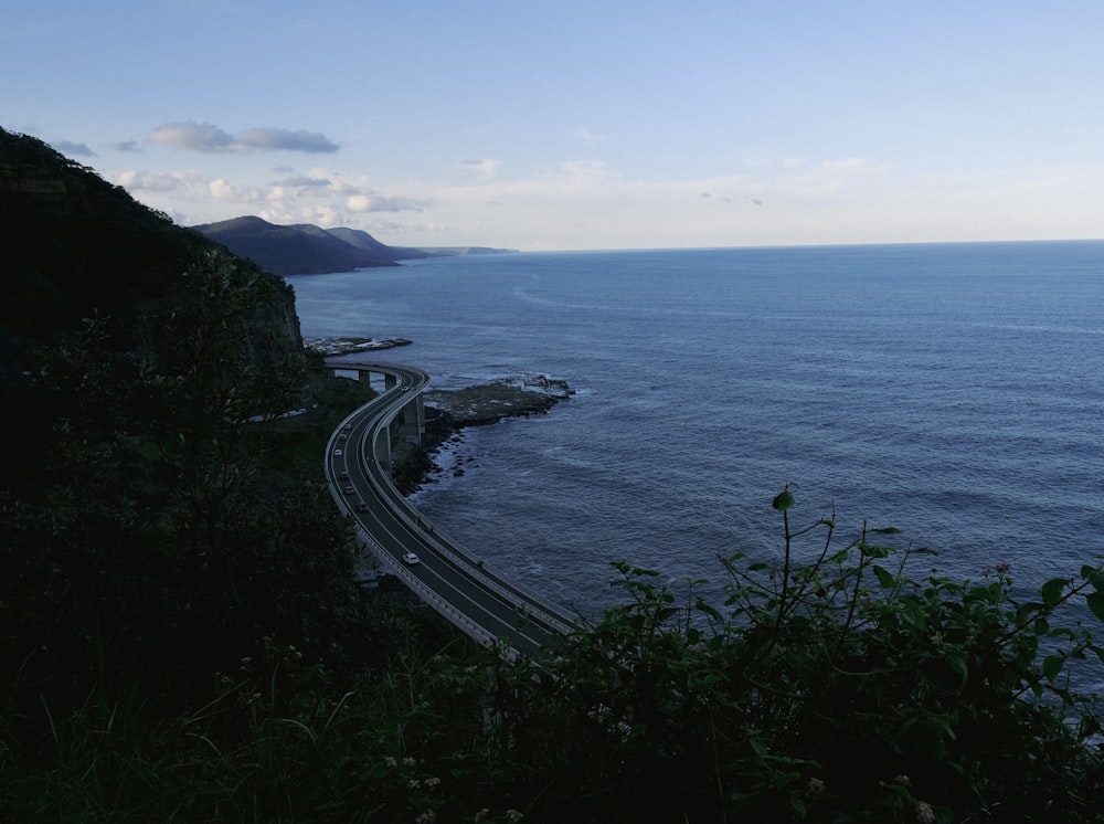 a scenic view of a highway next to the ocean