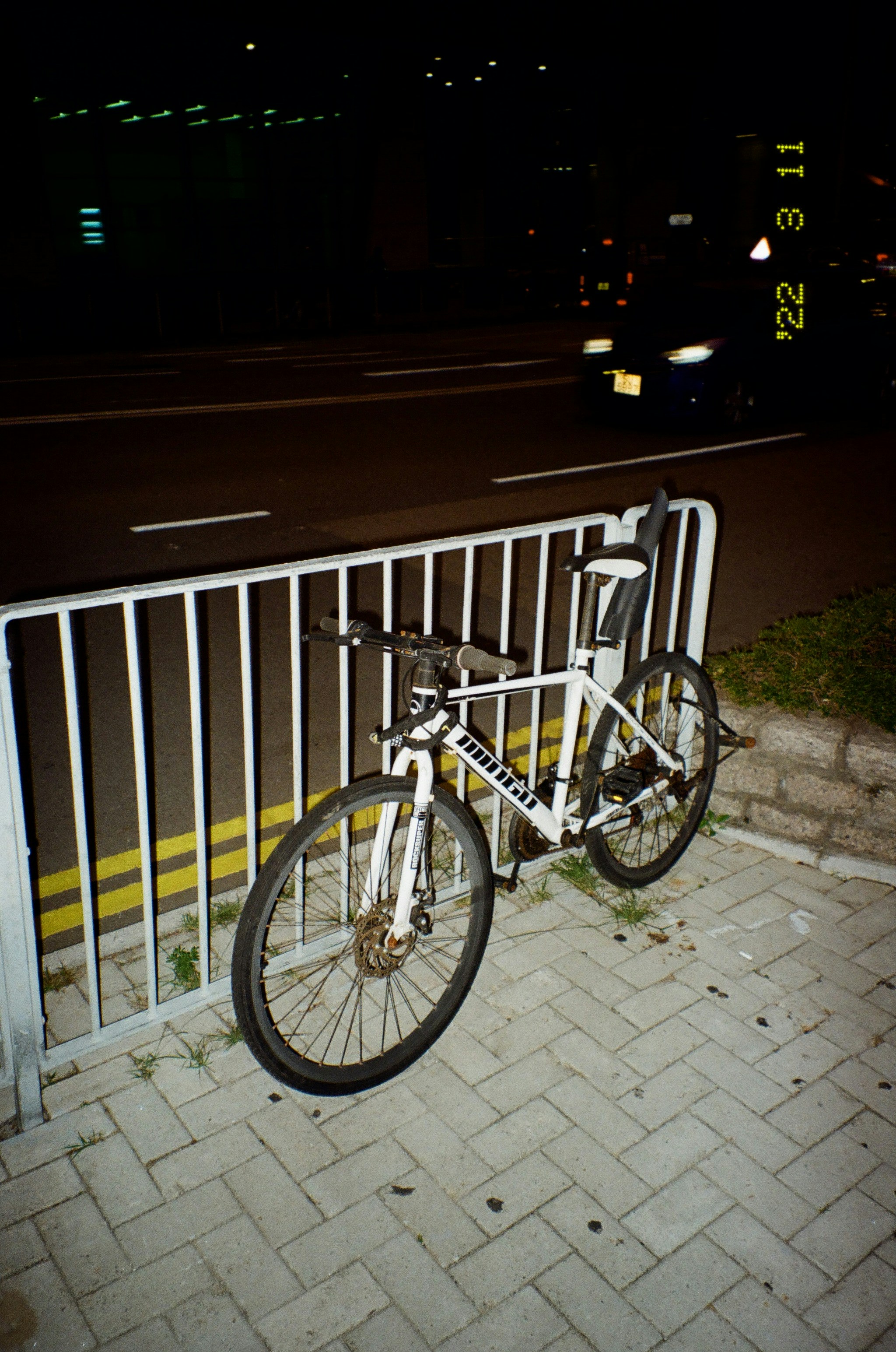 a white bicycle parked on a sidewalk next to a fence