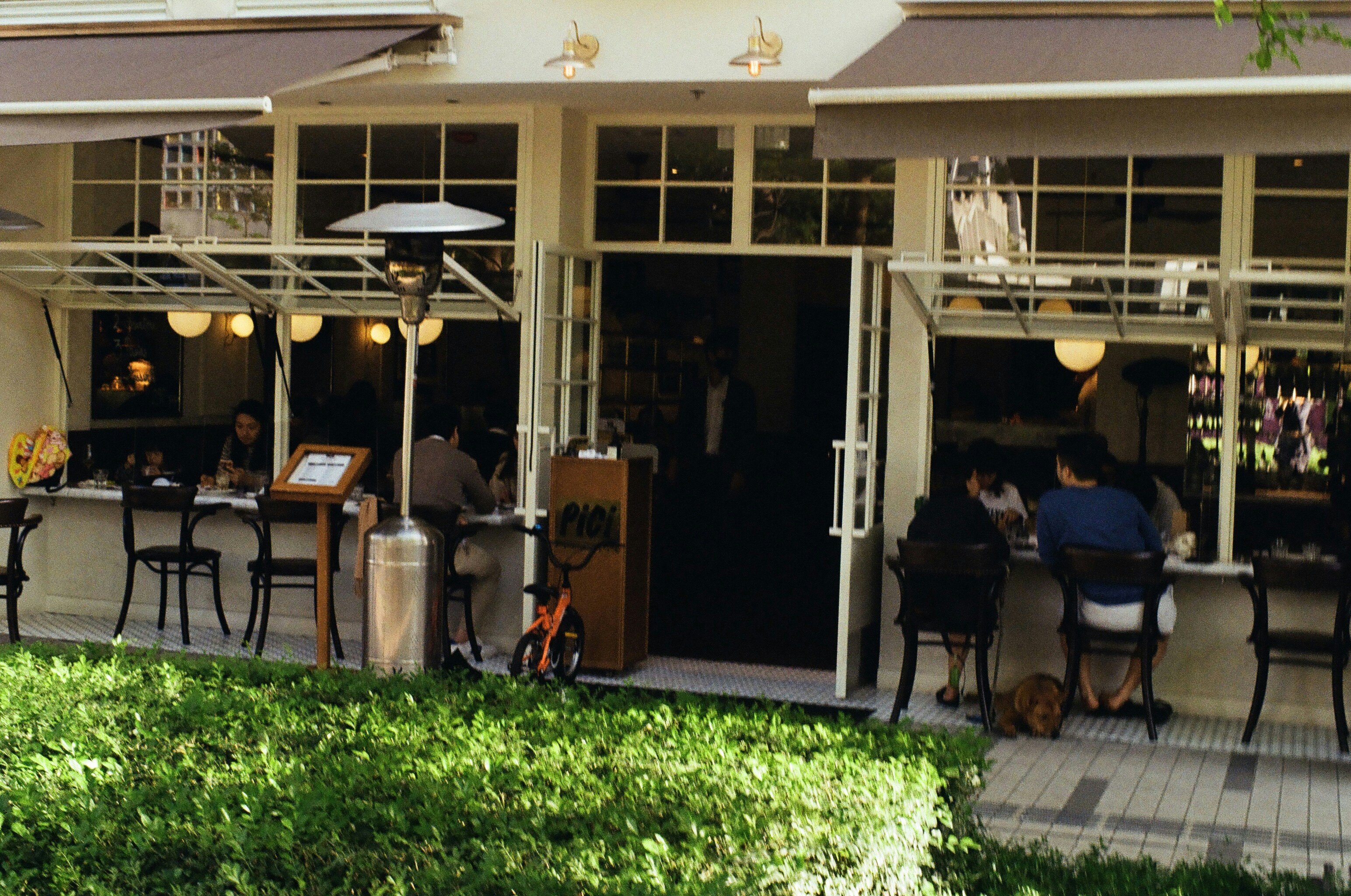 a group of people sitting at a table outside of a restaurant