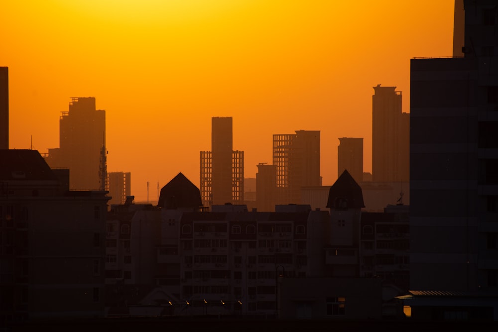 the sun is setting over a city with tall buildings