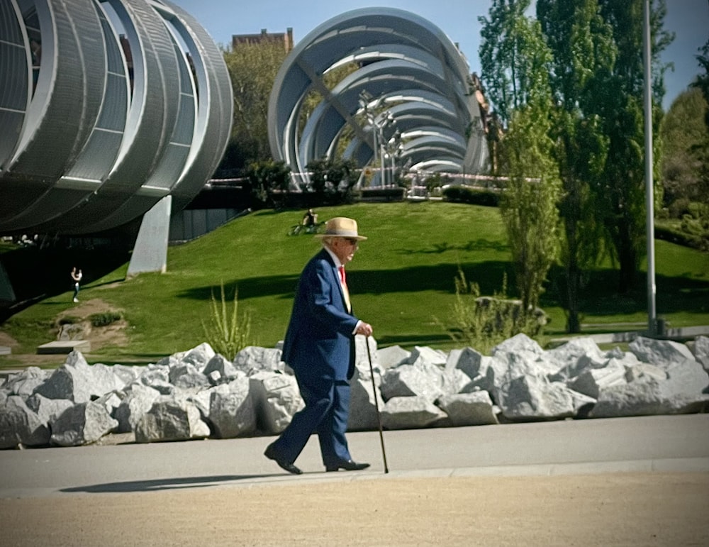 a man in a suit and hat walking down a street