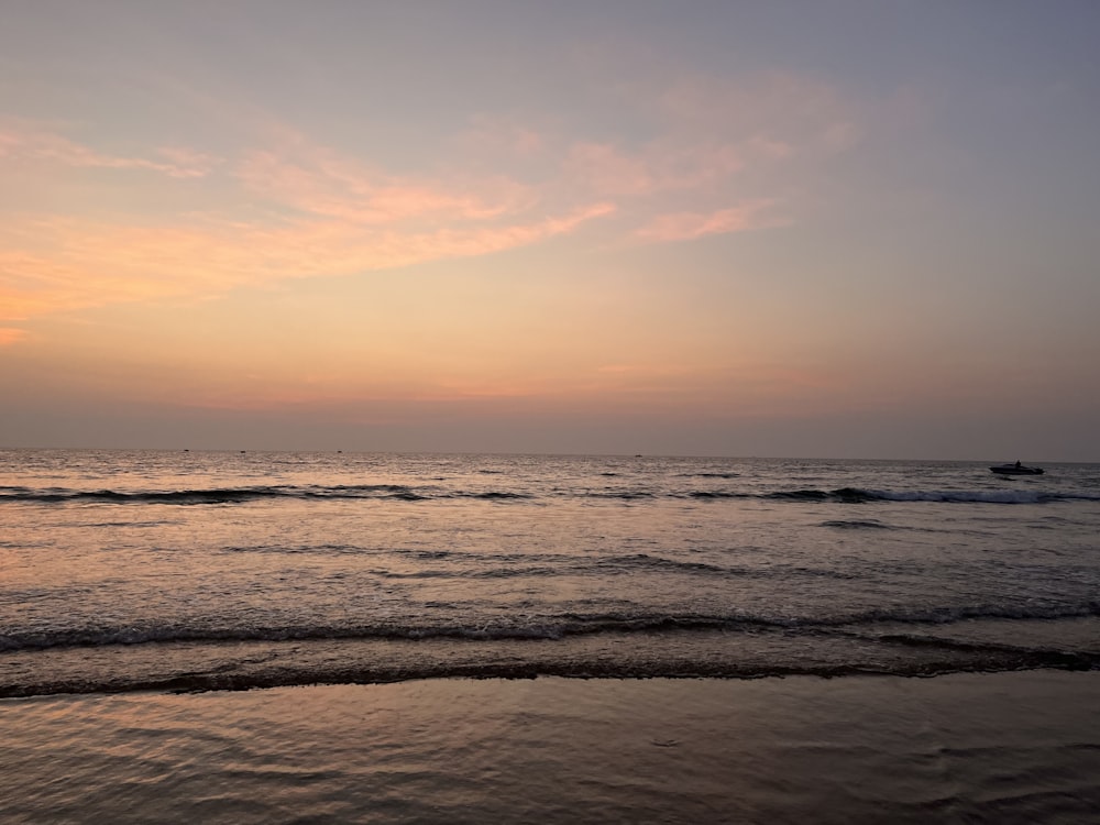 a sunset over the ocean with a boat in the distance