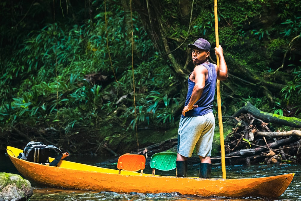 a man standing on a yellow boat in a river