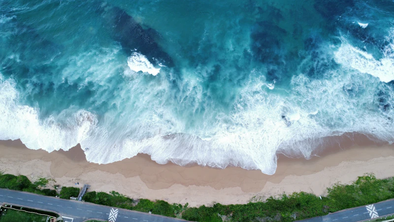 Overhead view of surf breaking onto Umdloti beach beside the beach road